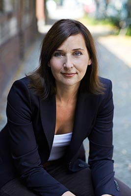 Jeanette Deloch sitzend in leicht vorgebeugter Haltung